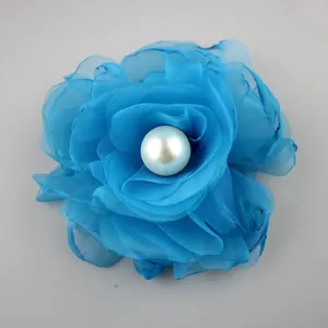 Detail of bright blue handmade chiffon rose with central pearl for garment accessories