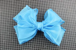 Detail of multi-layered light blue organza bow accessory on professional cutting mat