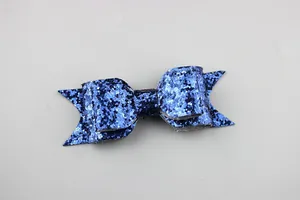 Close-up of a dark blue glitter bow clip showing multi-layer sequins and fishtail design