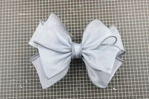 Close-up of light blue layered gauze bow shoe accessory with fine dark grey overlock edges