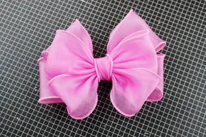 Detail showing multi-layer pink organza bow with fine edges on a professional cutting mat