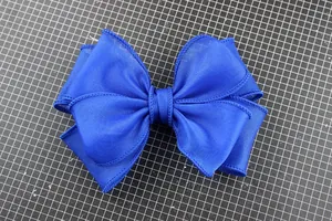 Detailed view of layered navy blue handmade bow shoe and corsage accessory in satin finish