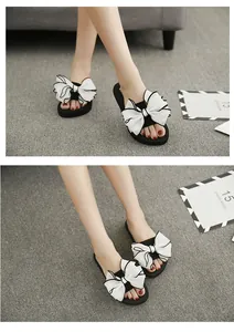 Detail of white fabric oversized bow on black platform flip flops for summer wear