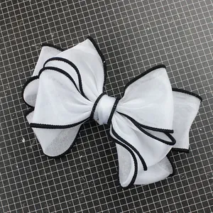 Large white layered organza bow shoe accessory with black contrasting edges