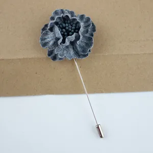 Detailed macro view of navy blue fabric flower lapel pin with long silver metal needle