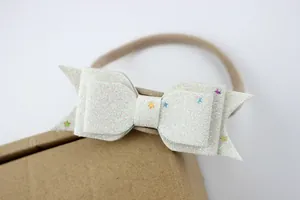 Detailopname van witte glitter strik hoofdband met kleurrijke sterrenpailletten voor baby