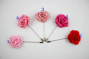 Dettaglio di cinque spille a fiore in tessuto fatte a mano in varie tonalità di rosa e rosso
