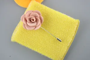 Macro shot of dusty pink fabric flower lapel pin for men on yellow knit background