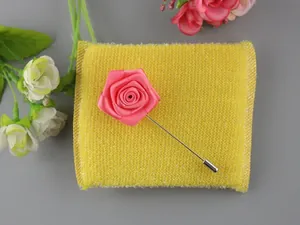Dettaglio di una spilla a rosa in raso rosa fatta a mano con una lunga spilla in metallo