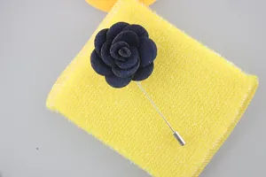 Detailed view of dark blue fabric camellia brooch with silver long pin on yellow support