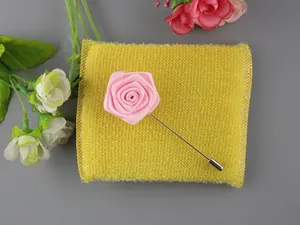 Dettaglio spilla a fiore in tessuto rosa con ago lungo argentato e cappuccio per abiti
