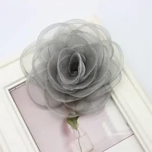 Dettaglio di una spilla a rosa in pizzo grigio con petali di organza stratificati e rifiniti