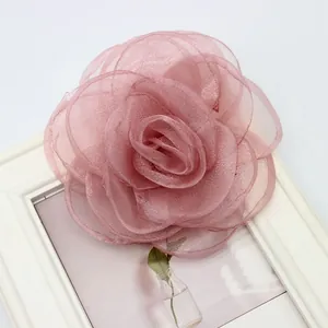 Dettaglio di una spilla a rosa in organza rosa cipria fatta a mano con petali 3D stratificati