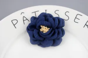 Detailed close-up of dark blue handmade fabric camellia flower with cream stamen