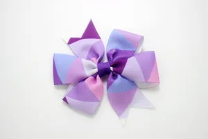 Detail of handmade grosgrain ribbon hair bow with colorful geometric triangle pattern