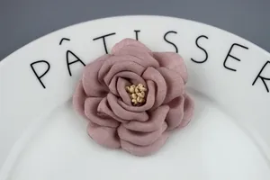 Detail of handmade fabric rose flower brooch with Morandi pink petals and yellow stamens