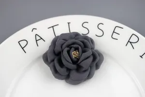 Macro view of a dark grey handmade fabric camellia flower with realistic yellow stamens