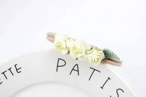 Detail of three cream fabric roses and green leaf on a beige elastic nylon headband
