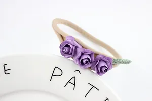 Detailed close-up of purple paper roses on a stretchy nylon baby headband accessory