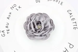 Detailed close-up of a 7.5cm grey satin camellia fabric flower with white pearl stamens