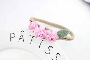 Detail of baby headband featuring three pink paper roses and soft elastic nylon strap