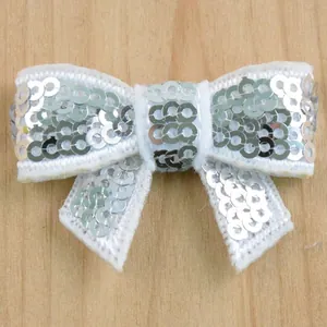 Macro shot of silver sequins on a white fabric butterfly bow for DIY hair accessories