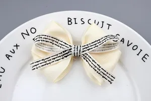 Elegant cream grosgrain hair bow with French script print on a decorative plate