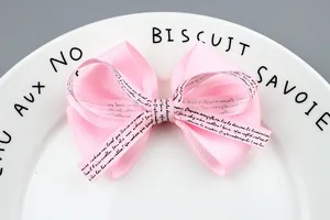 Close-up of pink layered grosgrain ribbon bow with elegant script ribbon detailing