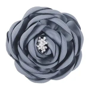 Close-up of handmade grey-blue fabric peony flower brooch with layered petals and white stamen