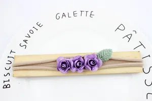 Elastic baby headband with three purple fabric roses and green leaf on khaki nylon strap