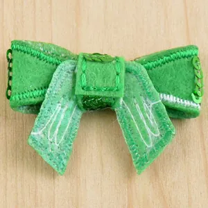 Detail view of green sequined bow accessory with machine stitching on felt material
