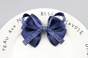 Close-up of a navy blue ribbed ribbon bow hair accessory with white printed lettering