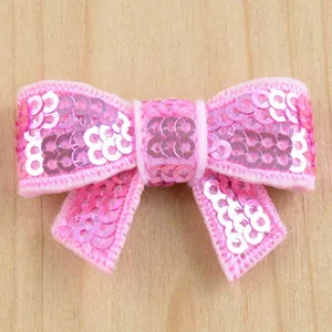 Pink sequin bow accessory for DIY hair clips on a minimalist light wood background