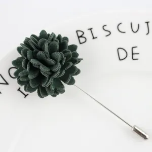 Vue macro de la broche fleur en laine vert foncé avec détail de longue aiguille argentée