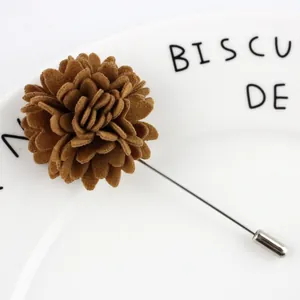 Vue macro d'une broche fleur en feutre marron avec longue épingle argentée sur céramique