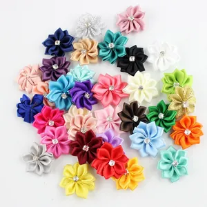 Flat lay of colorful DIY handmade polyester ribbon flowers with sparkling center rhinestones