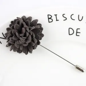 Broche fleur en tissu gris foncé élégante avec longue épingle argentée sur assiette blanche