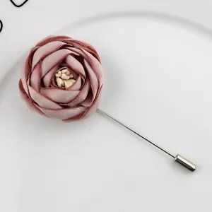 Close-up of handmade dusty rose fabric flower lapel pin with silver-tone long needle