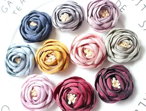 Dettaglio di 10 fiori in tessuto fatti a mano con bordi bruciati e stami in un vassoio