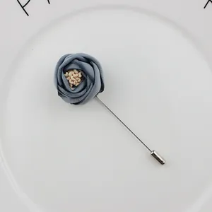 Classic blue fabric rose boutonnière for men with silver long pin on a white ceramic tray