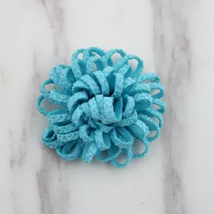 Close-up of a handmade blue fabric flower with layered petals on white marble surface