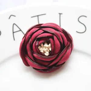 Dettaglio macro di camelia in tessuto rosso vino con petali stratificati e stame bianco