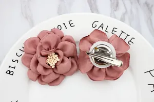 Détail de fleur en tissu rose poudré avec clip en métal et épingle à broche au dos