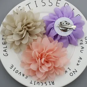 Detail of fabric flower brooches in cream, lilac, and pink with dual-purpose metal clips