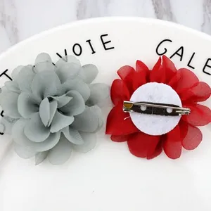 Macro detail of fabric flower brooches showing petal texture and metal pin closure