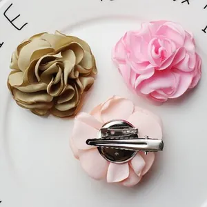 Detail of handmade satin fabric flower brooches and hair clips in champagne and pink