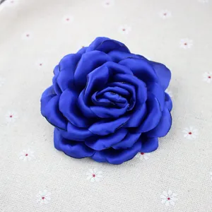 Detailed close-up of a royal blue chiffon flower brooch with black burnt edges