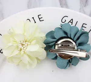 Detail view of fabric flower pins in beige and blue with metallic dual-use clips