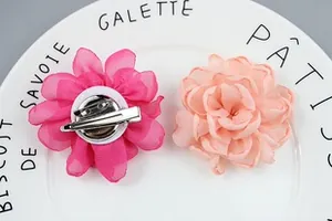 Detail of rose red and orange fabric flower brooches with dual-purpose metal hair clips