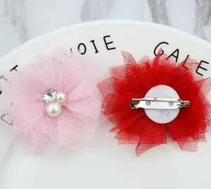 Detail of fabric flower brooch with pearls and metal safety pin on marble background
